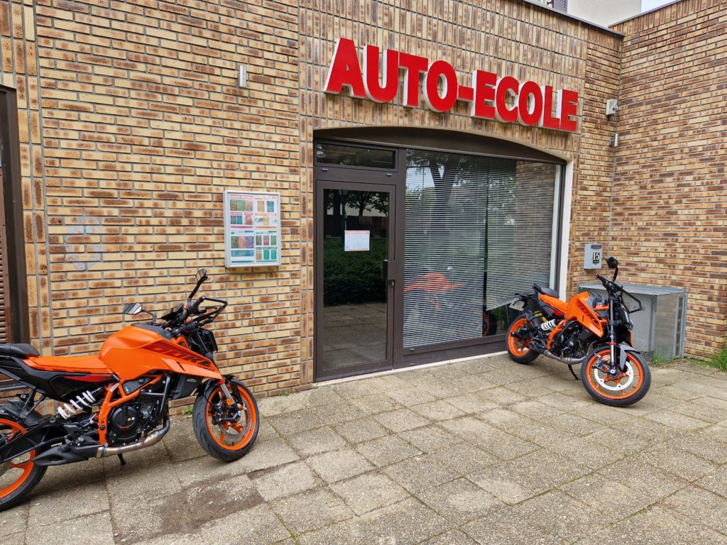 Deux motos KTM 390 Duke devant l'entrée de l'auto-école Sucy Conduites, 15 avenue Charles de Gaulle