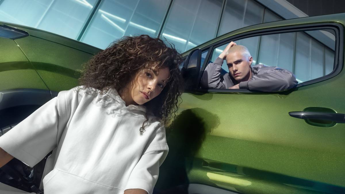 Une jeune conductrice et son accompagnateur à côté de leur voiture